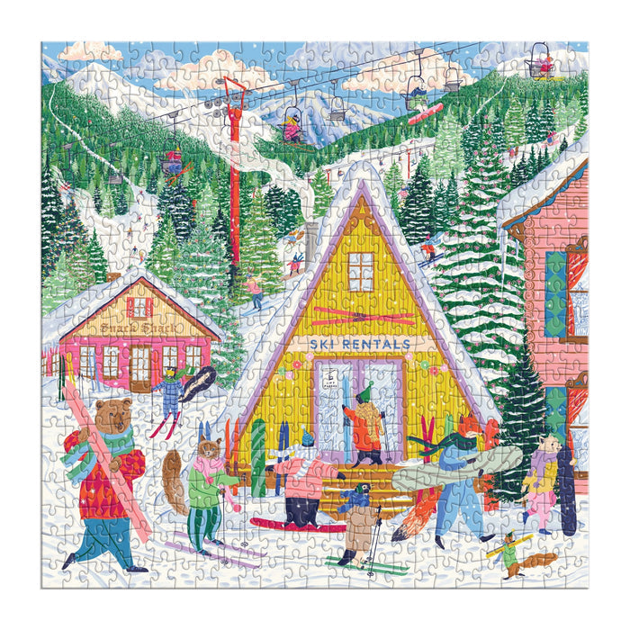 The Ski Village 500 Piece Puzzle by Emily Taylor features a lively winter scene with people renting skis, carrying gear, and getting ready to ski near a yellow "Ski Rentals" shop, set among snowy trees, slopes, and chairlifts.