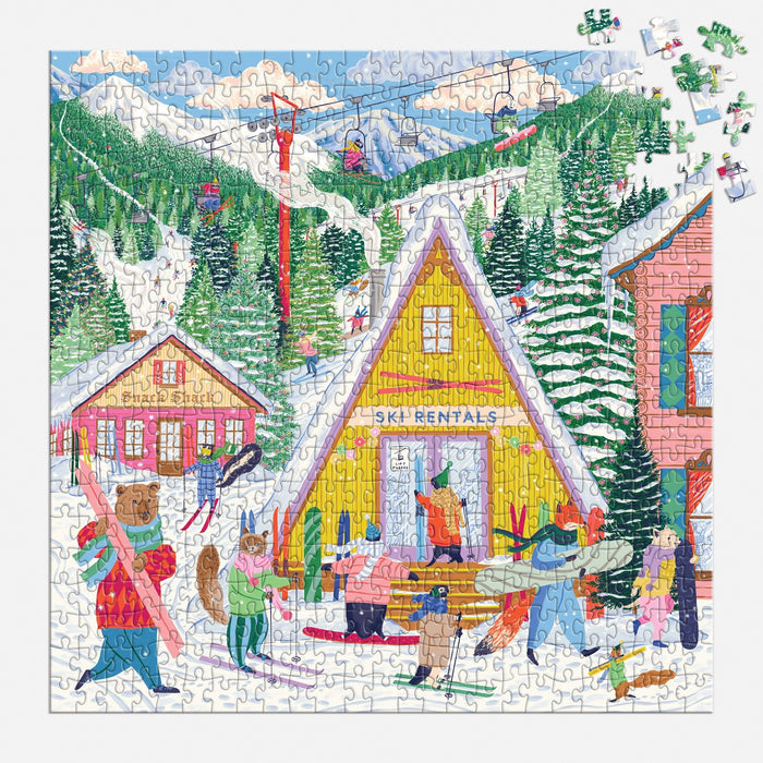 The Emily Taylor Ski Village 500 Piece Puzzle features a vibrant ski resort scene with people in winter gear by a yellow “Ski Rentals” cabin, snowy trees, and ski lifts on a mountain slope. Some pieces are missing.