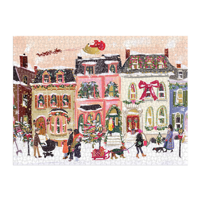 The Nysha Lilly Snowfall on Main Street 1000 Piece Foil Puzzle features people and dogs in a festive, snowy village as Santa’s sleigh flies above. Shiny foil accents highlight wreaths and bows on the decorated buildings.