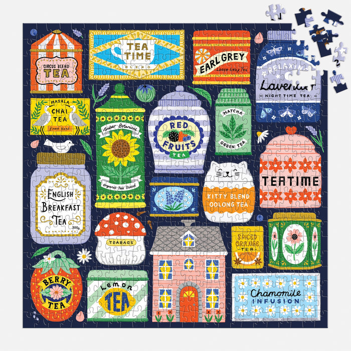 A nearly finished Spot of Tea 500 Piece Puzzle by Holly Maguire displays vibrant tea tins—Earl Grey, Red Fruits, Matcha, Chai, Berry, Chamomile—with a few pieces left in the top right corner.