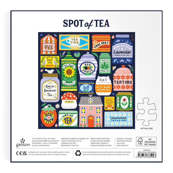 The Spot of Tea 500 Piece Puzzle by Holly Maguire features whimsical tea tins, teacups, and a teapot labeled Green Tea, Earl Grey, and Chai. A flower-filled house sits at the center on a navy blue background.