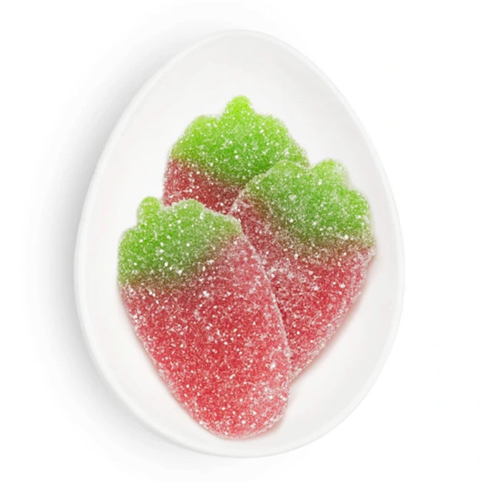 Red and green gummy candy shaped like strawberries on a white plate.