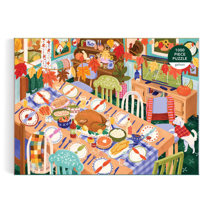 The Thankful Table 1000 Piece Puzzle by Carla Ellis features a festive dining scene with a large turkey, vibrant side dishes, autumn leaves decor, and a white dog by the table—all bathed in warm, welcoming light.