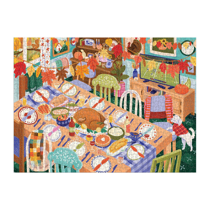 The Carla Ellis Thankful Table 1000 Piece Puzzle features a festive dining room set for Thanksgiving with autumn décor, delicious dishes, a dog on the floor, and a family preparing to enjoy their meal.