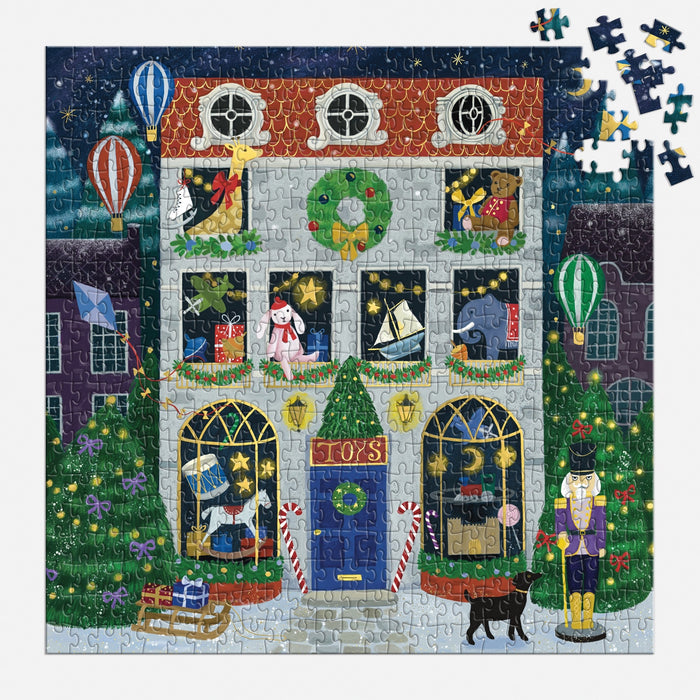A partially completed Twilight Toy Shop 500 Piece Foil Puzzle by Bex Parkin shows a festive toy store with toys, hot air balloons, a nutcracker, black dog, presents, and Christmas trees. Several pieces are missing in the top right.