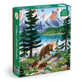 The Kim Smith Valley of the Peaks 1000 Piece Puzzle features a bear with cubs walking by a mountain lake, with snow-capped peaks and wildlife in the background.