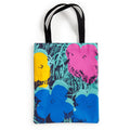 The Warhol Flowers Volume 3 Canvas Tote Bag by the Andy Warhol Foundation for The Visual Arts features an abstract floral design in yellow, pink, and blue on a green and black background, with sturdy black handles.