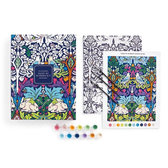 The William Morris Brother Rabbit 9 x 12" Paint by Number Kit features white rabbits, blue birds, and colorful flowers. It includes a box, coloring guide, three brushes, and small paint pots arranged in a row.