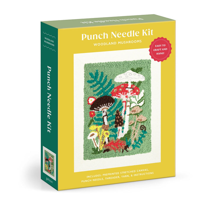 The Anja Riebensahm Woodland Mushrooms Punch Needle Kit comes in a yellow and green box featuring a vibrant mushroom and plant design. Included are canvas, punch needle, threader, yarn, and instructions.