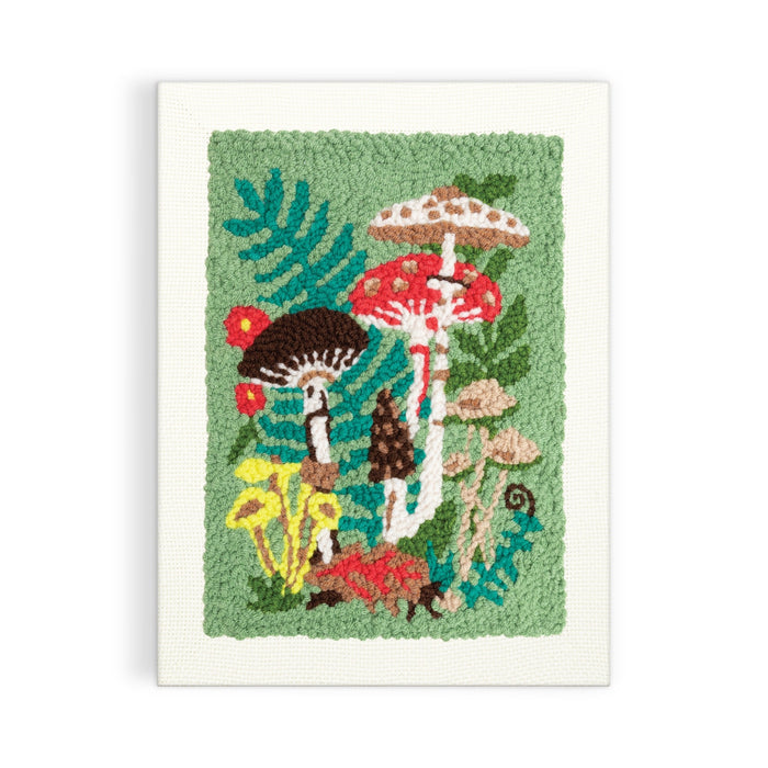 The Woodland Mushrooms Punch Needle Kit by Anja Riebensahm features colorful mushrooms and ferns on a green background, showcasing red, brown, yellow, and white tones for a vibrant woodland scene.