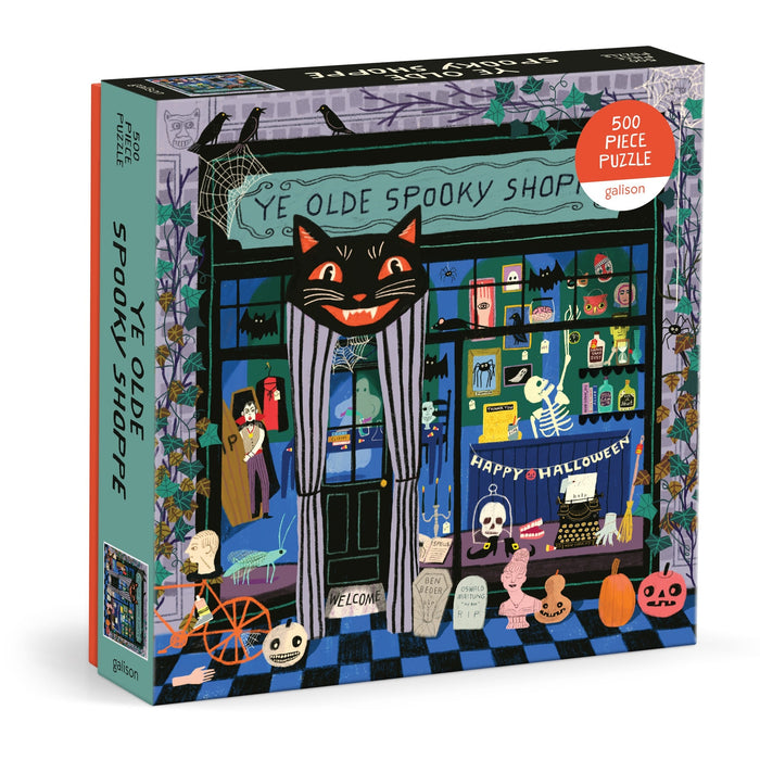 The Anne Bentley Ye Olde Spooky Shoppe 500 Piece Puzzle features a vibrant Halloween shop scene with a black cat sign, ghosts, pumpkins, skeletons, and festive decorations.