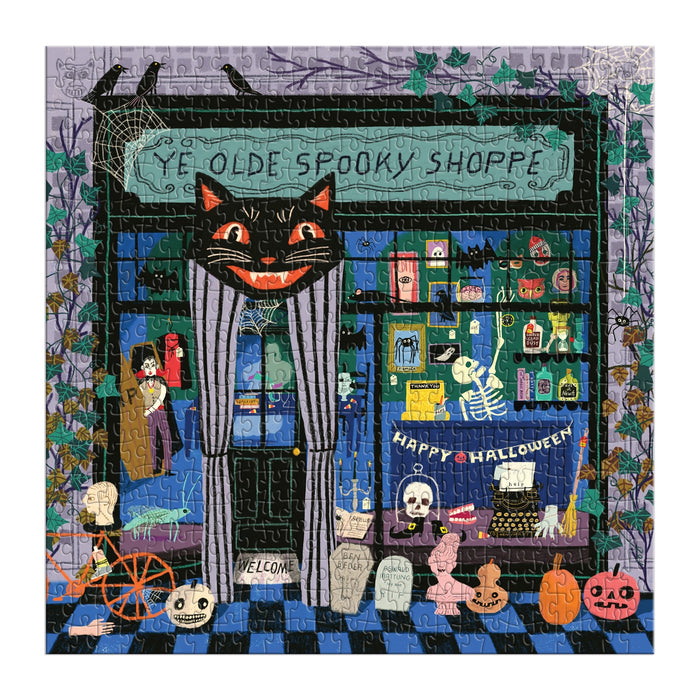 The Anne Bentley Ye Olde Spooky Shoppe 500 Piece Puzzle features a Halloween store scene with a grinning cat sign, skeletons, potions, cobwebs, pumpkins, and spooky items in the window and outside.