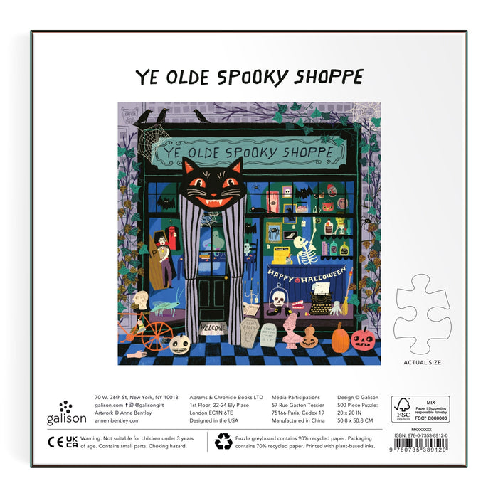Illustration of Ye Olde Spooky Shoppe by Anne Bentley: a Halloween-themed store with a big black cat sign, spooky decor, pumpkins, skeletons, and festive items in the window; 500 piece puzzle info borders the image.